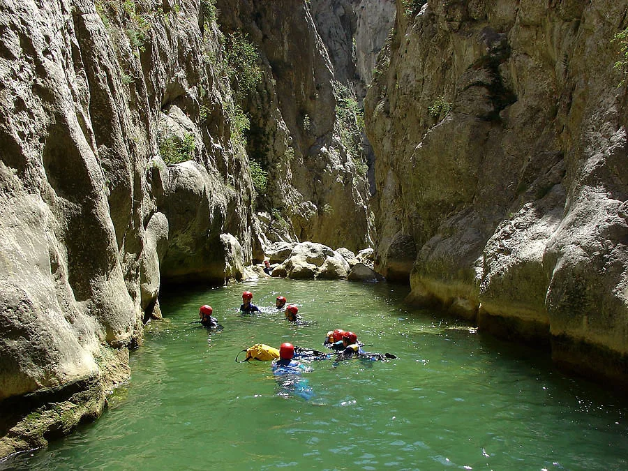 Groupe de canyonistes en combinaison néoprène progressant dans une gorge aux eaux turquoise