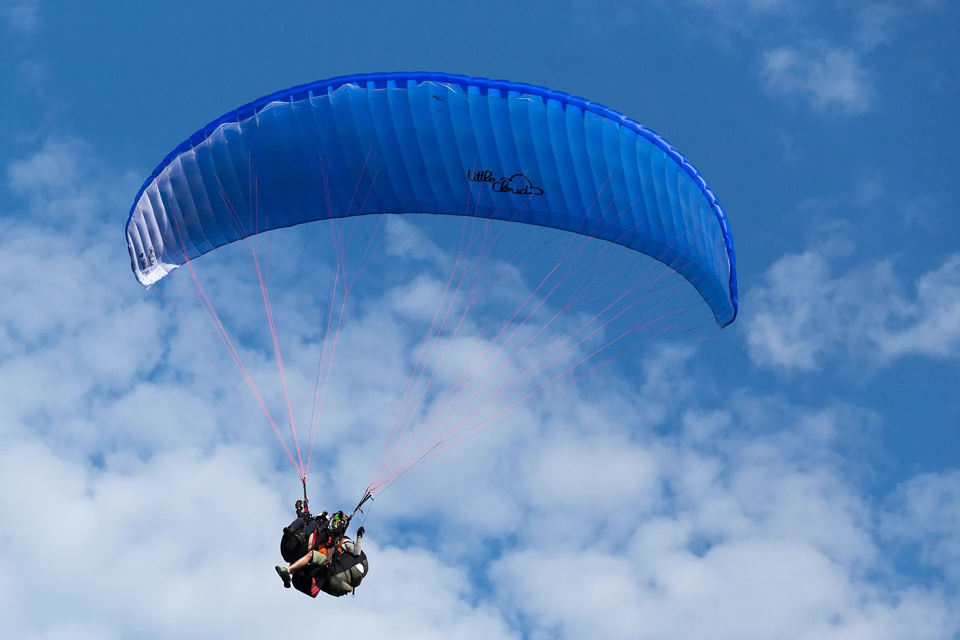 Parapente biplace en vol sous une voile bleue